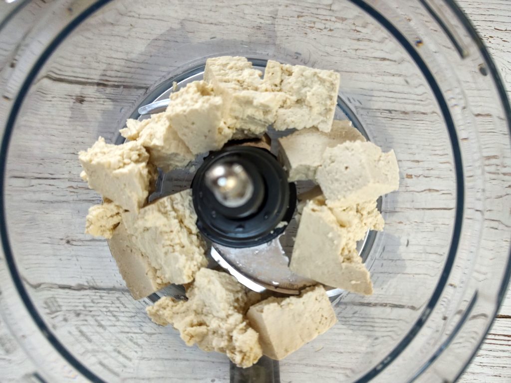 Chunks of tofu in the bowl of a food processor.