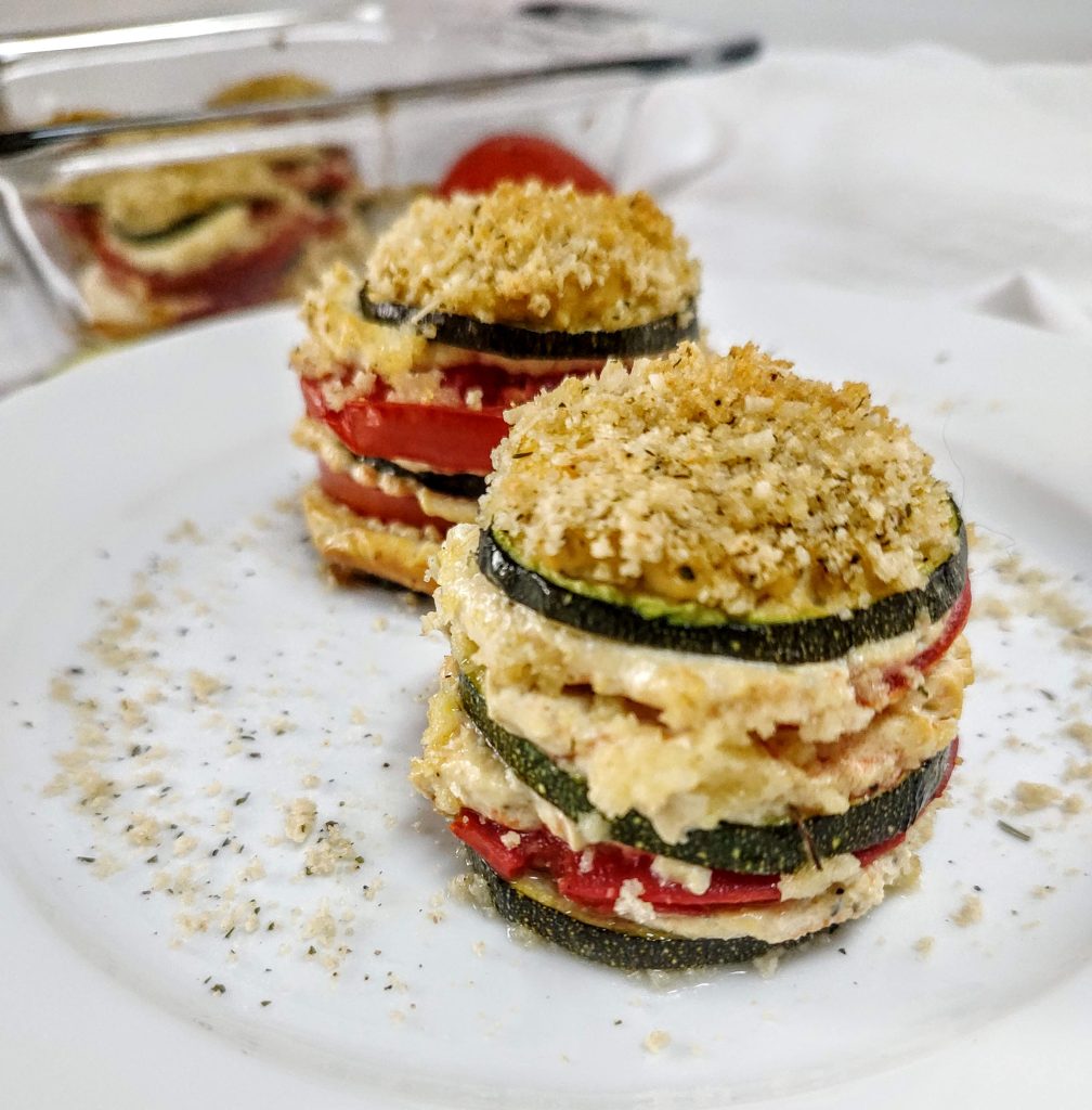 Two cooked zucchini tomato lasagna stacks on a white plate.